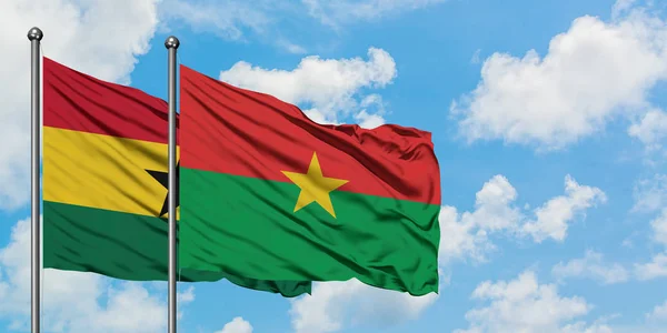 Bandera de Ghana y Burkina Faso ondeando en el viento contra el cielo azul nublado blanco juntos. Concepto diplomático, relaciones internacionales . — Foto de Stock
