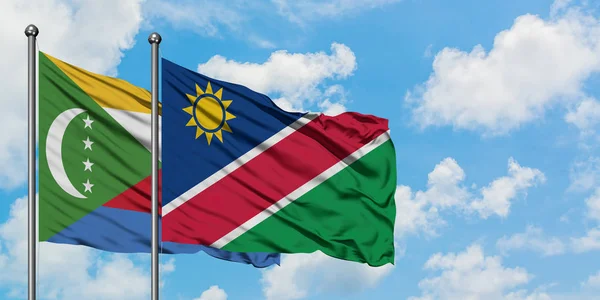 Comoren en Namibië vlag zwaaien in de wind tegen witte bewolkte blauwe hemel samen. Diplomatie concept, internationale betrekkingen. — Stockfoto