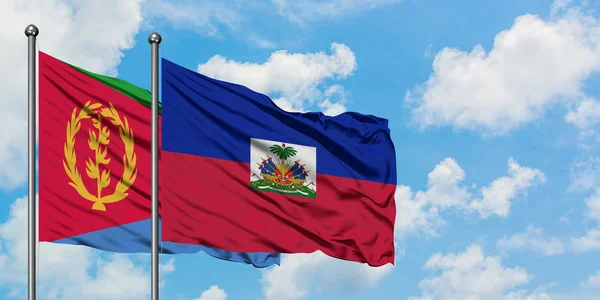 Bandera de Eritrea y Haití ondeando en el viento contra el cielo azul nublado blanco juntos. Concepto diplomático, relaciones internacionales . — Foto de Stock
