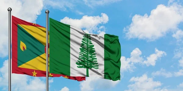 Bandera de Granada y Norfolk Island ondeando en el viento contra el cielo azul nublado blanco juntos. Concepto diplomático, relaciones internacionales . — Foto de Stock