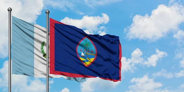 Bandera de Guatemala y Guam ondeando en el viento contra el cielo azul nublado blanco juntos. Concepto diplomático, relaciones internacionales . — Foto de Stock