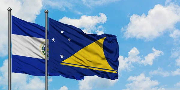 Bandera de El Salvador y Tokelau ondeando en el viento contra el cielo azul nublado blanco juntos. Concepto diplomático, relaciones internacionales . — Foto de Stock