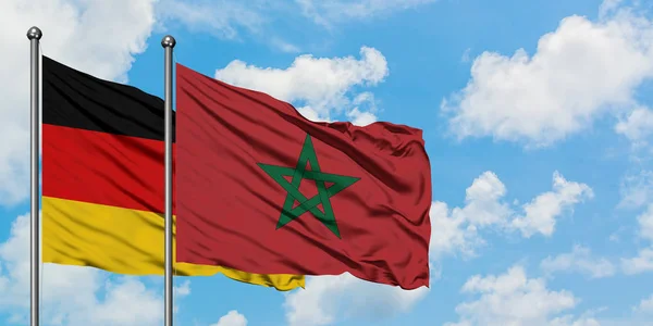 Bandera de Alemania y Marruecos ondeando en el viento contra el cielo azul nublado blanco juntos. Concepto diplomático, relaciones internacionales . — Foto de Stock