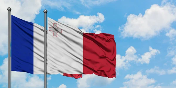 Bandera de Francia y Malta ondeando en el viento contra el cielo azul nublado blanco juntos. Concepto diplomático, relaciones internacionales . —  Fotos de Stock