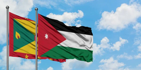 Bandera de Granada y Jordania ondeando en el viento contra el cielo azul nublado blanco juntos. Concepto diplomático, relaciones internacionales . — Foto de Stock