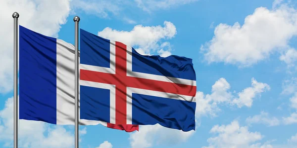 Bandera de Francia e Islandia ondeando en el viento contra el cielo azul nublado blanco juntos. Concepto diplomático, relaciones internacionales . —  Fotos de Stock