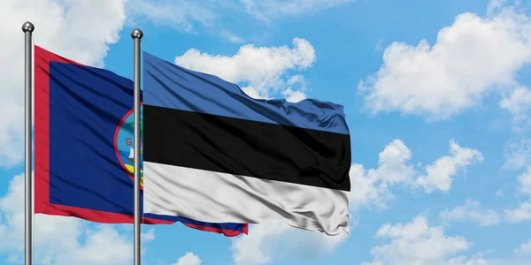 Guam ve Estonya bayrağı birlikte beyaz bulutlu mavi gökyüzüne karşı rüzgarda sallayarak. Diplomasi kavramı, uluslararası ilişkiler. — Stok fotoğraf