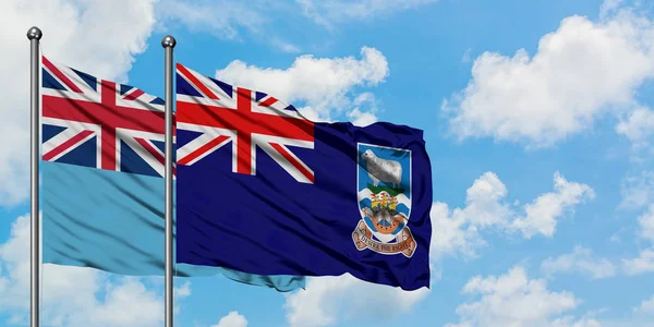 Bandeira das Ilhas Fiji e Falkland agitando no vento contra o céu azul nublado branco juntos. Conceito de diplomacia, relações internacionais . — Fotografia de Stock