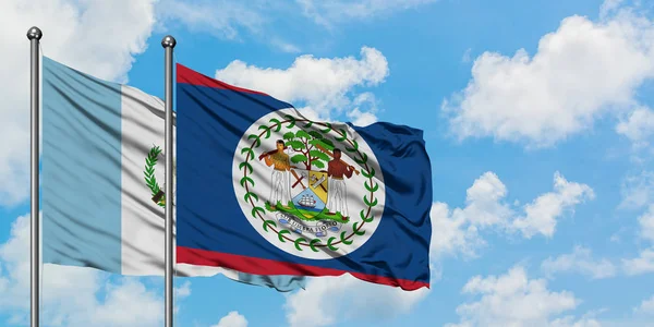 Bandera de Guatemala y Belice ondeando en el viento contra el cielo azul nublado blanco juntos. Concepto diplomático, relaciones internacionales . — Foto de Stock