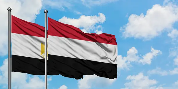 Bandera de Egipto y Yemen ondeando en el viento contra el cielo azul nublado blanco juntos. Concepto diplomático, relaciones internacionales . — Foto de Stock