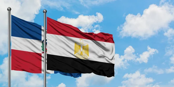 Bandera de República Dominicana y Egipto ondeando en el viento contra el cielo azul nublado blanco juntos. Concepto diplomático, relaciones internacionales . — Foto de Stock