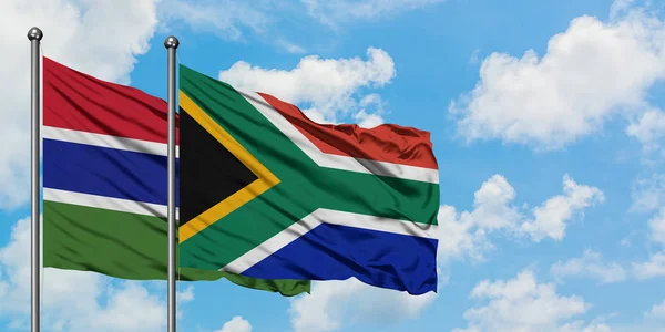 Vlajka Gambie a Jihoafrické republiky mávaje větrem proti bílé zamračené modré obloze. Diplomacie, mezinárodní vztahy. — Stock fotografie