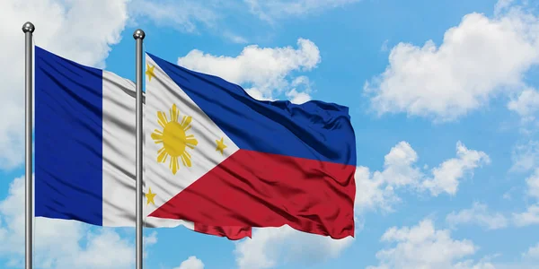 Bandera de Francia y Filipinas ondeando en el viento contra el cielo azul nublado blanco juntos. Concepto diplomático, relaciones internacionales . — Foto de Stock