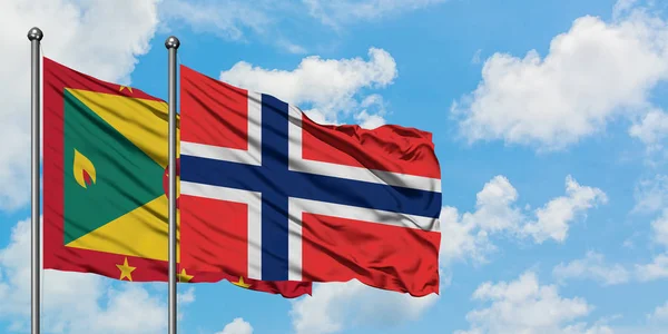 Bandera de Granada y Bouvet Islands ondeando en el viento contra el cielo azul nublado blanco juntos. Concepto diplomático, relaciones internacionales . — Foto de Stock