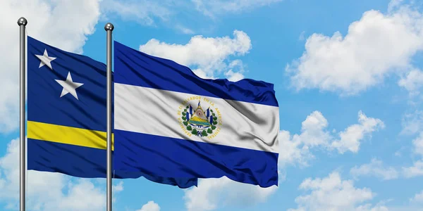 Curaçao und El Salvador-Flagge wehen gemeinsam im Wind vor dem wolkenverhangenen blauen Himmel. Diplomatie-Konzept, internationale Beziehungen. — Stockfoto