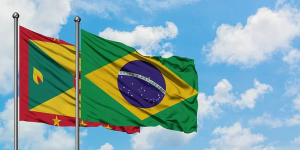 Bandera de Granada y Brasil ondeando en el viento contra el cielo azul nublado blanco juntos. Concepto diplomático, relaciones internacionales . — Foto de Stock