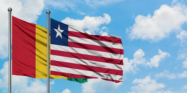 一緒に白い曇り青い空に対して風に手を振るギニアとリベリアの旗。外交概念、国際関係. — ストック写真