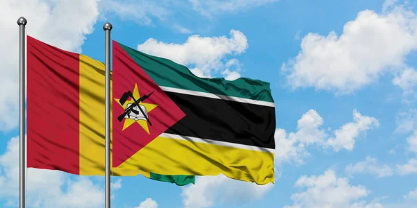 一緒に白い曇り青い空に対して風に手を振るギニアとモザンビークの旗。外交概念、国際関係. — ストック写真