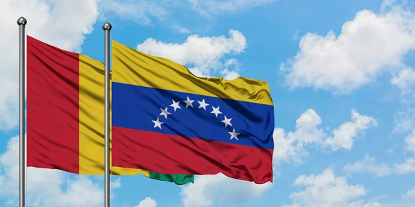 Guinea and Venezuela flag waving in the wind against white cloudy blue sky together. Diplomacy concept, international relations. — Stock Photo, Image