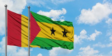 Gine ve Sao Tome ve Principe bayrağı birlikte beyaz bulutlu mavi gökyüzüne karşı rüzgarda sallayarak. Diplomasi kavramı, uluslararası ilişkiler.