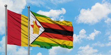 Gine ve Zimbabve bayrağı birlikte beyaz bulutlu mavi gökyüzüne karşı rüzgarda sallayarak. Diplomasi kavramı, uluslararası ilişkiler.