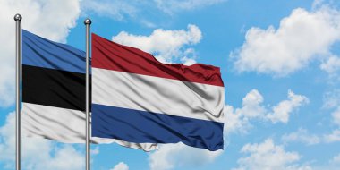 Estonya ve Hollanda bayrağı birlikte beyaz bulutlu mavi gökyüzüne karşı rüzgarsal sallayarak. Diplomasi kavramı, uluslararası ilişkiler.