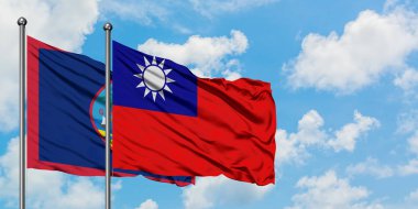 Guam ve Tayvan bayrağı birlikte beyaz bulutlu mavi gökyüzüne karşı rüzgarda sallayarak. Diplomasi kavramı, uluslararası ilişkiler.