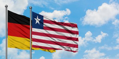 Almanya ve Liberya bayrağı birlikte beyaz bulutlu mavi gökyüzüne karşı rüzgarda sallayarak. Diplomasi kavramı, uluslararası ilişkiler.