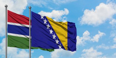 Gambiya ve Bosna Hersek bayrağı birlikte beyaz bulutlu mavi gökyüzüne karşı rüzgarda sallayarak. Diplomasi kavramı, uluslararası ilişkiler.