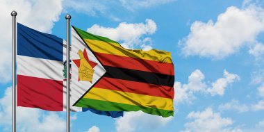 Dominik Cumhuriyeti ve Zimbabve bayrağı birlikte beyaz bulutlu mavi gökyüzüne karşı rüzgarda sallayarak. Diplomasi kavramı, uluslararası ilişkiler.
