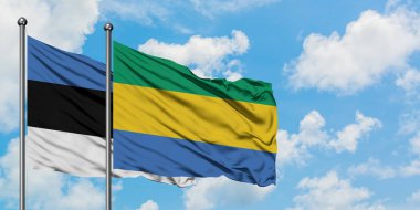 Estonya ve Gabon bayrağı birlikte beyaz bulutlu mavi gökyüzüne karşı rüzgarda sallayarak. Diplomasi kavramı, uluslararası ilişkiler.