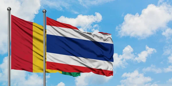 Guinea e Thailandia bandiera sventolando nel vento contro bianco cielo blu nuvoloso insieme. Concetto di diplomazia, relazioni internazionali . — Foto Stock