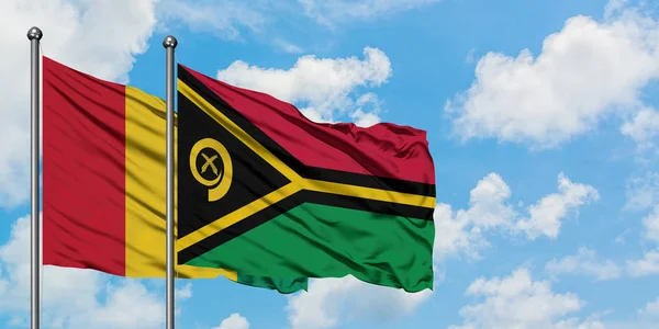 기니와 바누아투 깃발이 하얀 흐린 푸른 하늘을 배경으로 바람에 흔들리고 있습니다. 외교 개념, 국제 관계. — 스톡 사진