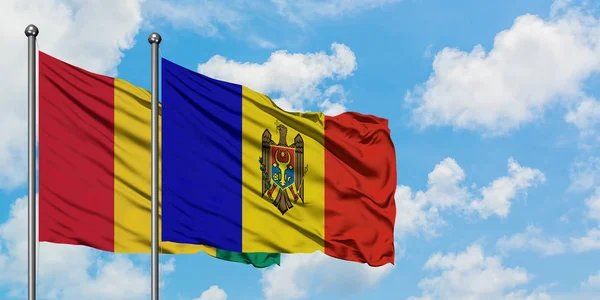 Bandera de Guinea y Moldavia ondeando en el viento contra el cielo azul nublado blanco juntos. Concepto diplomático, relaciones internacionales . — Foto de Stock