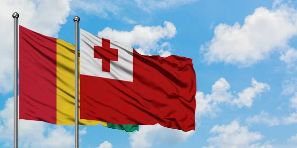几内亚和汤加国旗在风中飘扬，与白云蓝天相交加。外交概念、国际关系. — 图库照片