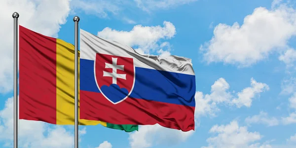 Drapeau de la Guinée et de la Slovaquie agitant dans le vent contre ciel bleu nuageux blanc ensemble. Concept de diplomatie, relations internationales . — Photo
