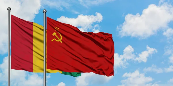 Guinea och Sovjetunionen flagga vifta i vinden mot vit grumlig blå himmel tillsammans. Diplomatisk koncept, internationella relationer. — Stockfoto