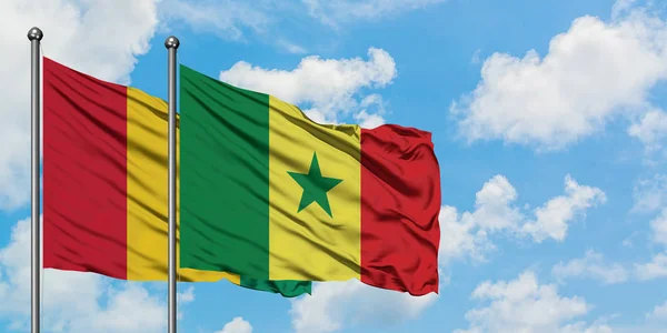 Guinea och Senegal sjunker vifta i vinden mot vit grumlig blå himmel tillsammans. Diplomatisk koncept, internationella relationer. — Stockfoto