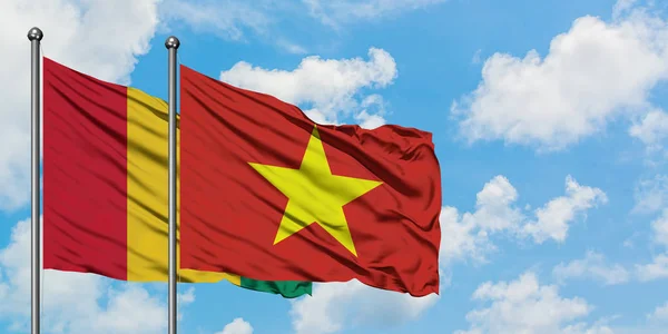Флаг Гвинеи и Вьетнама размахивает ветром против белого облачно-голубого неба вместе. Концепция дипломатии, международные отношения . — стоковое фото