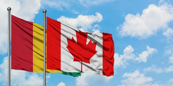 La bandiera della Guinea e del Canada sventola nel vento contro il bianco cielo blu nuvoloso insieme. Concetto di diplomazia, relazioni internazionali . — Foto Stock