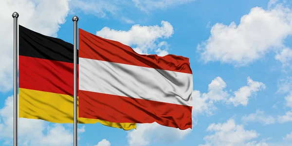 Bandeira da Alemanha e Áustria agitando no vento contra o céu azul nublado branco juntos. Conceito de diplomacia, relações internacionais . — Fotografia de Stock
