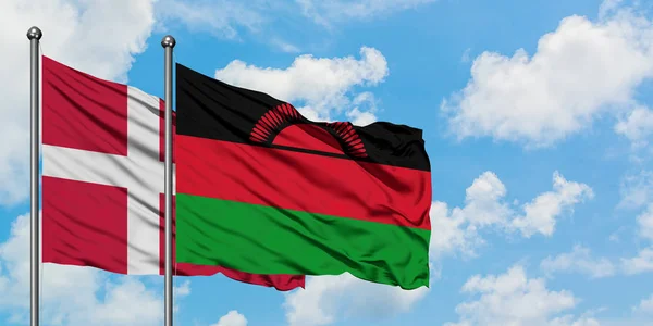 Dania i Malawi flagi machając w wiatr przed białym zachmurzone błękitne niebo razem. Koncepcja dyplomacji, stosunki międzynarodowe. — Zdjęcie stockowe