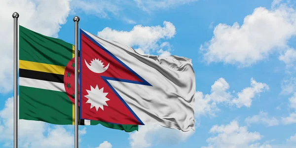 Bandera de Dominica y Nepal ondeando en el viento contra el cielo azul nublado blanco juntos. Concepto diplomático, relaciones internacionales . — Foto de Stock