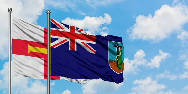 Guernsey a Montserrat praporce mávali ve větru proti bíle zatažené modré obloze. Diplomacie, mezinárodní vztahy. — Stock fotografie