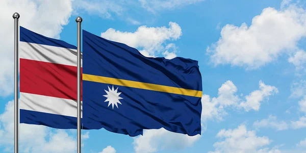 Bandera de Costa Rica y Nauru ondeando en el viento contra el cielo azul nublado blanco juntos. Concepto diplomático, relaciones internacionales . — Foto de Stock