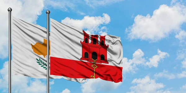 Cyprus en Gibraltar vlag zwaaien in de wind tegen witte bewolkte blauwe hemel samen. Diplomatie concept, internationale betrekkingen. — Stockfoto