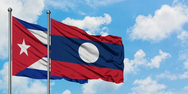 Cuba et le Laos drapeau agitant dans le vent contre ciel bleu nuageux blanc ensemble. Concept de diplomatie, relations internationales . — Photo
