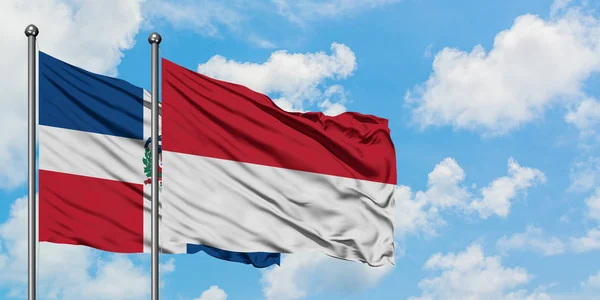 Bandera de República Dominicana e Indonesia ondeando en el viento contra el cielo azul nublado blanco juntos. Concepto diplomático, relaciones internacionales . — Foto de Stock