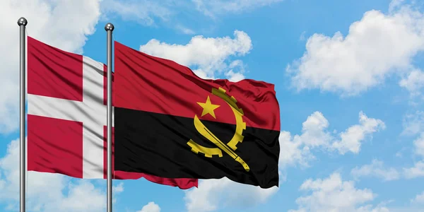 Bandeira da Dinamarca e Angola agitando no vento contra o céu azul nublado branco juntos. Conceito de diplomacia, relações internacionais . — Fotografia de Stock