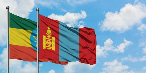 Etiopía y Mongolia bandera ondeando en el viento contra el blanco cielo azul nublado juntos. Concepto diplomático, relaciones internacionales . — Foto de Stock